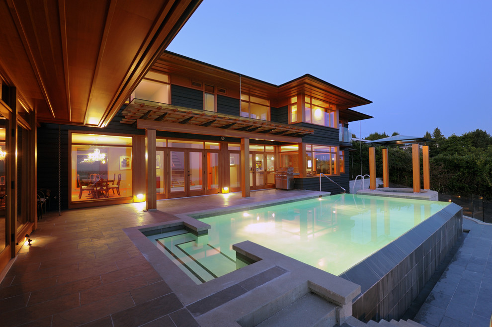 Cette image montre une grande piscine à débordement et arrière design rectangle avec un bain bouillonnant et du carrelage.