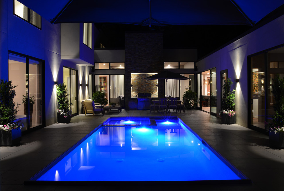 Foto di una grande piscina naturale minimalista rettangolare dietro casa con una vasca idromassaggio e piastrelle