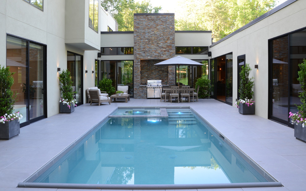 Exemple d'une grande piscine sur toit naturelle moderne rectangle avec du carrelage et un bain bouillonnant.
