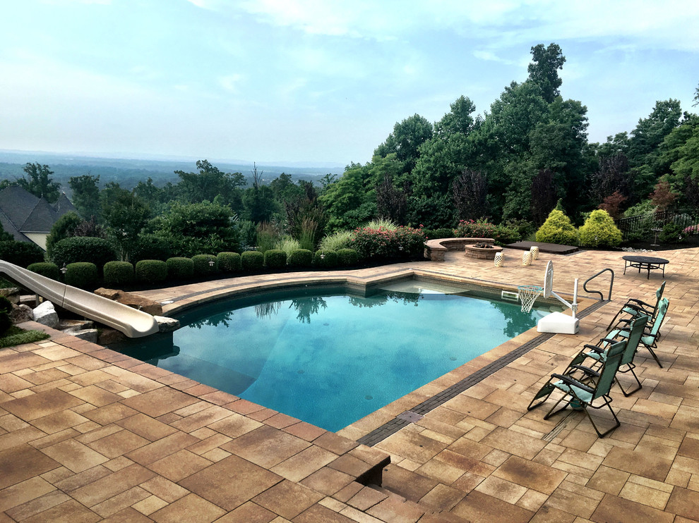 This is an example of a medium sized modern back custom shaped swimming pool in Philadelphia with a water slide and natural stone paving.