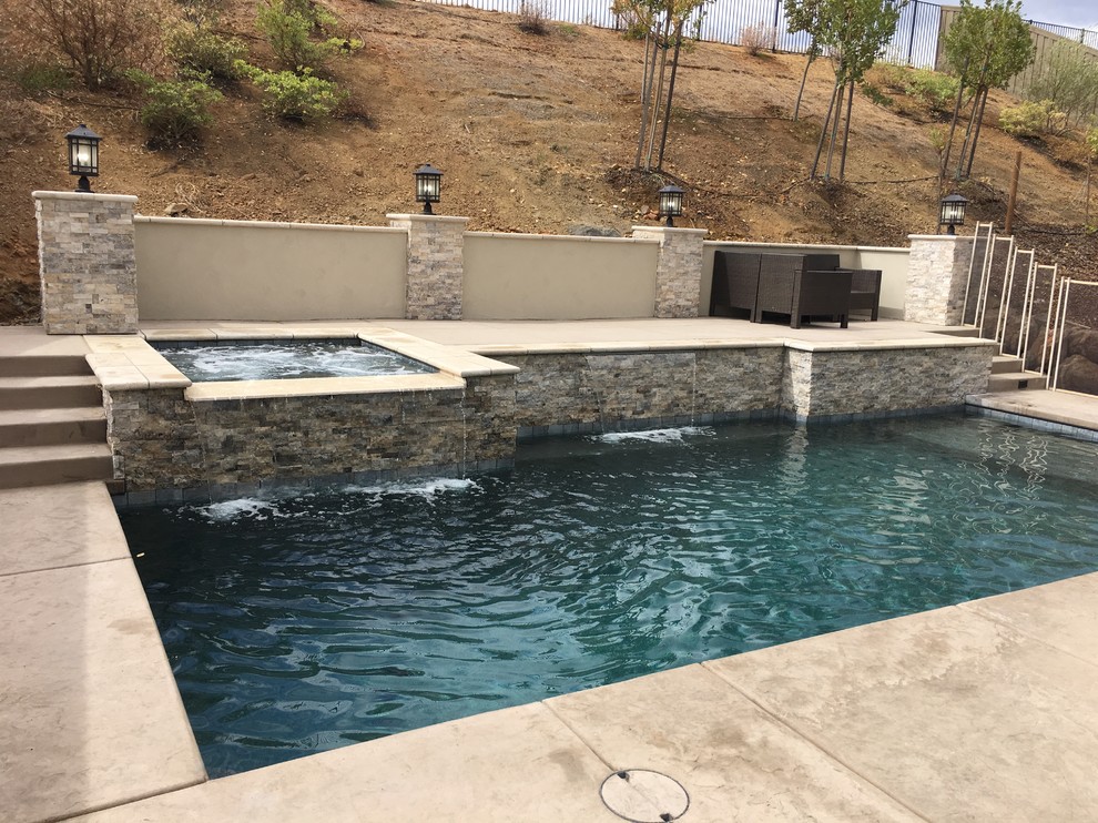 Foto di una piccola piscina monocorsia contemporanea rettangolare dietro casa con cemento stampato e una vasca idromassaggio