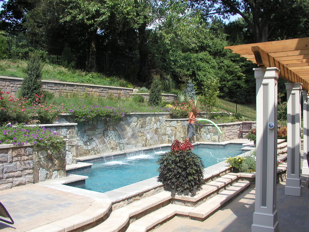 Diseño de piscina con fuente alargada minimalista de tamaño medio a medida en patio trasero con adoquines de hormigón