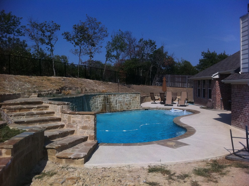 Immagine di una grande piscina monocorsia chic a "C" dietro casa con fontane e lastre di cemento