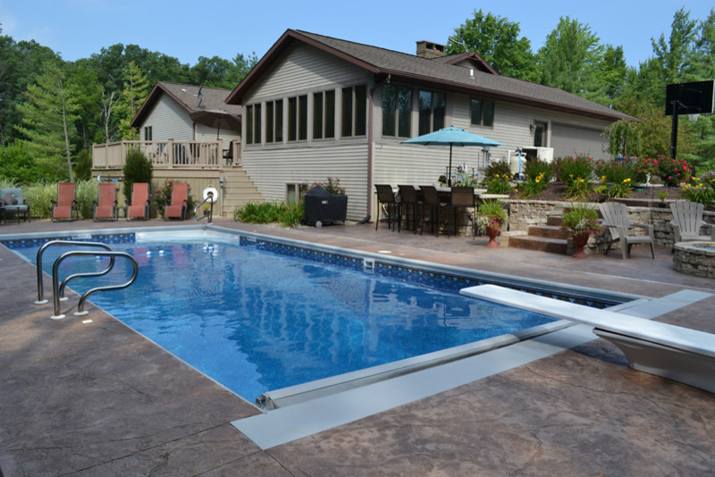 Example of a mid-sized classic backyard concrete and rectangular lap pool design in Other