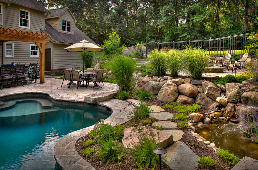 На фото: бассейн произвольной формы на заднем дворе в классическом стиле с покрытием из каменной брусчатки