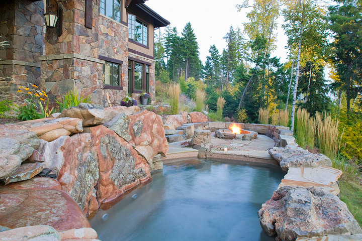 Réalisation d'une petite piscine naturelle et arrière chalet sur mesure avec des pavés en pierre naturelle et un point d'eau.