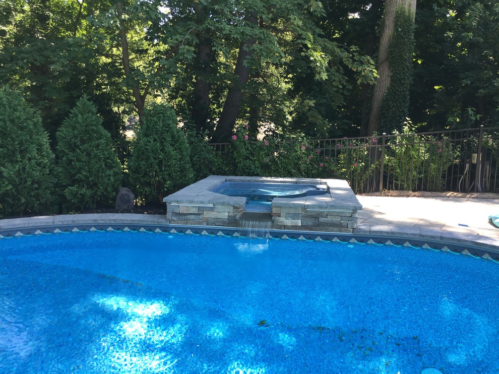 Immagine di una piscina classica a "C" dietro casa con una vasca idromassaggio