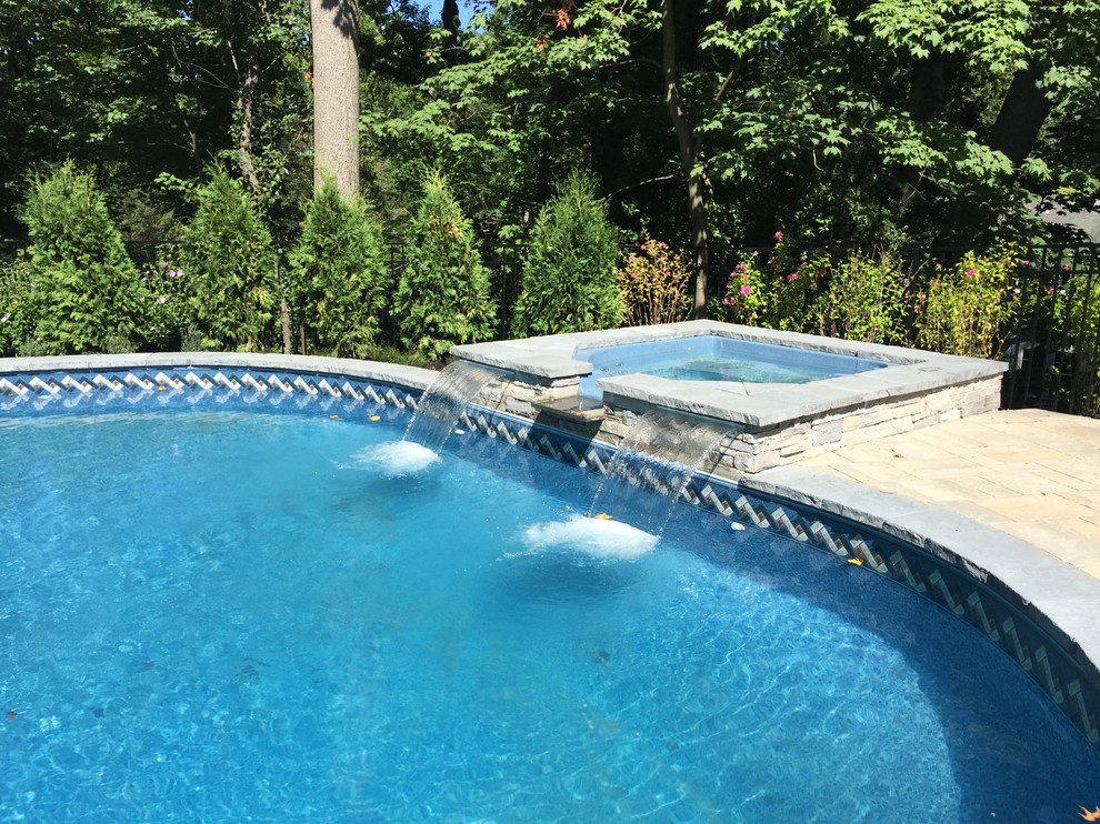 Foto di una piscina classica a "C" dietro casa con una vasca idromassaggio