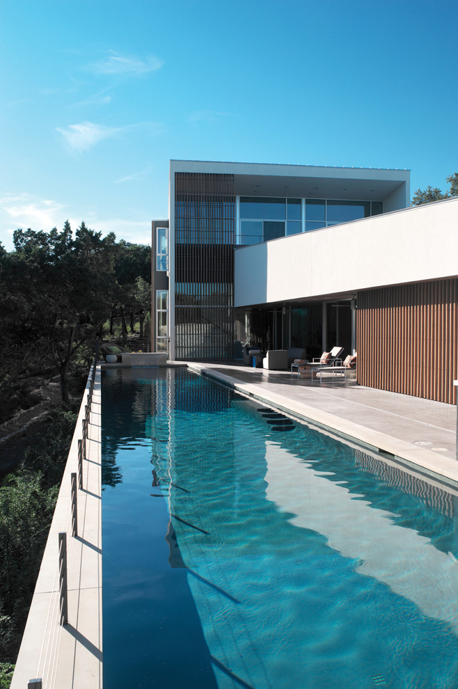Идея дизайна: большой спортивный, прямоугольный бассейн на заднем дворе в стиле модернизм с покрытием из бетонных плит