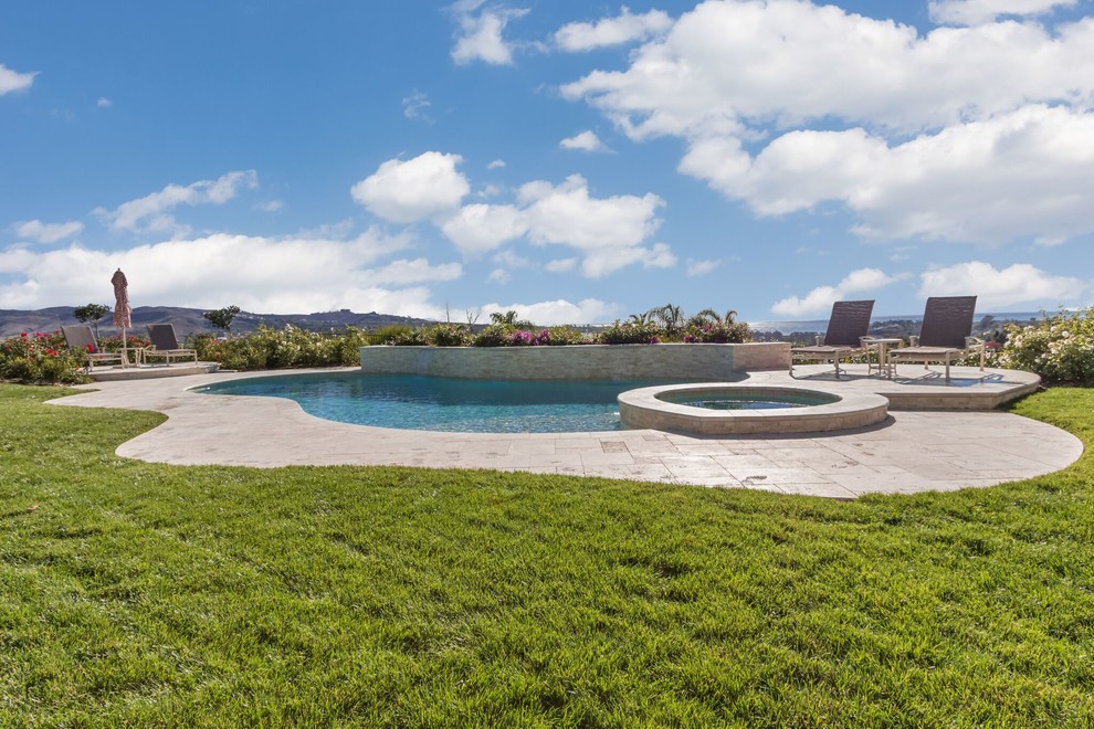 Ejemplo de piscina con fuente actual grande a medida en patio trasero con suelo de baldosas