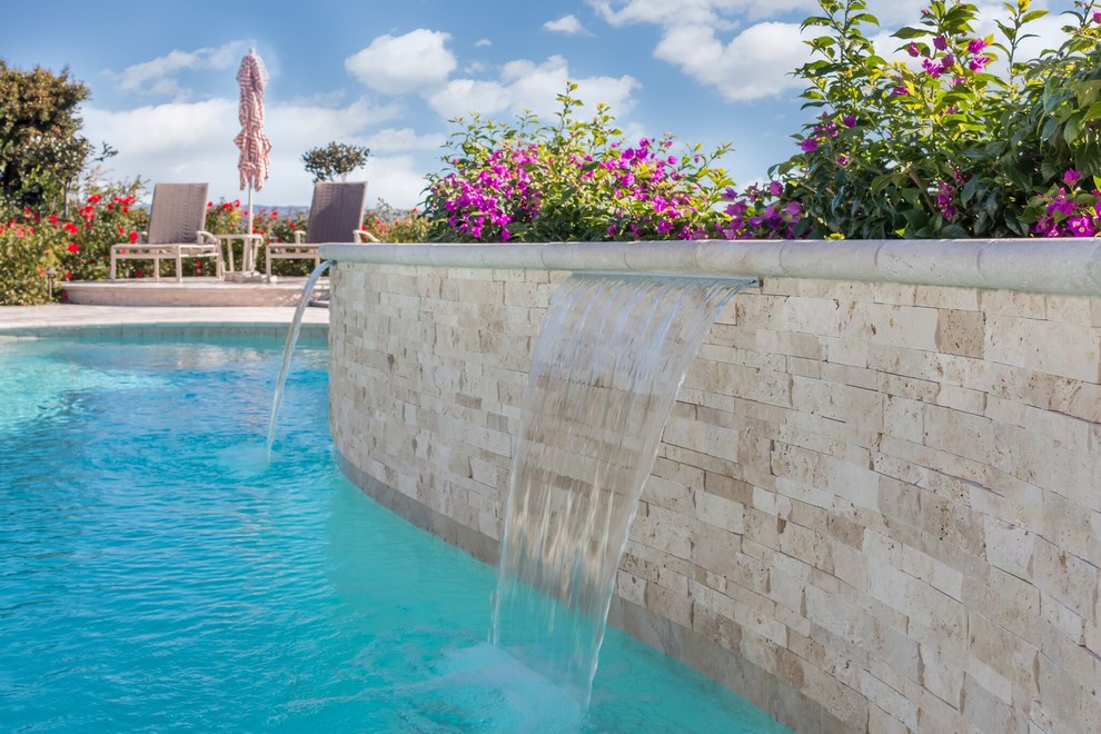 This is an example of a large contemporary back custom shaped swimming pool in Orange County with a water feature and tiled flooring.