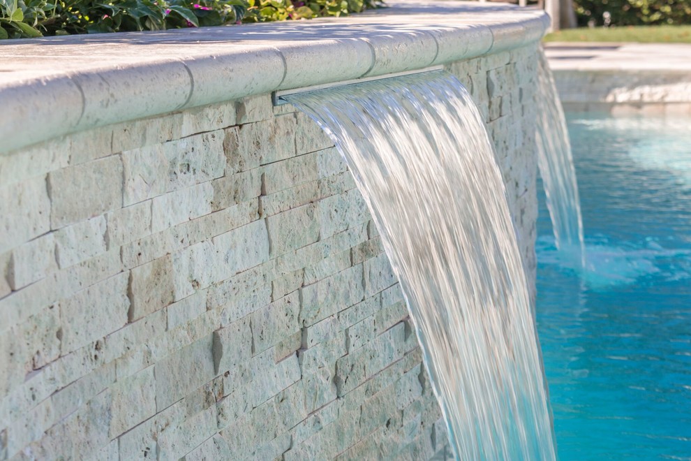 Immagine di una grande piscina design personalizzata dietro casa con fontane e piastrelle