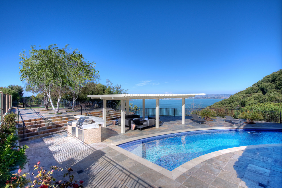 Idée de décoration pour une grande piscine naturelle et arrière méditerranéenne sur mesure avec un point d'eau et des pavés en pierre naturelle.