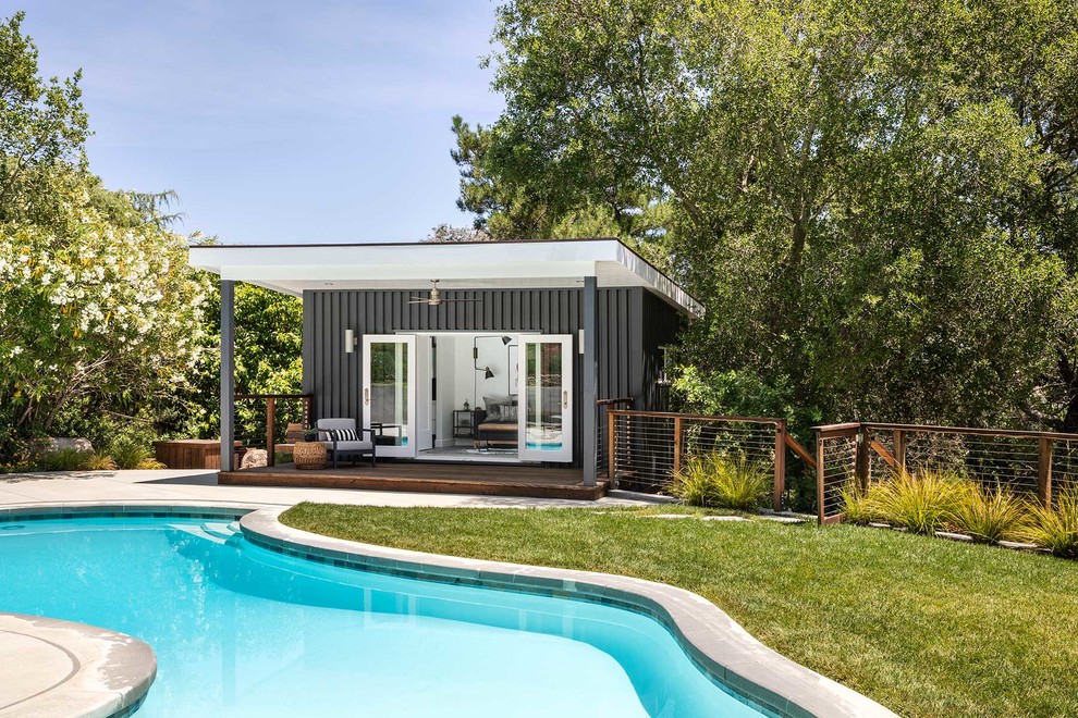 Идея дизайна: бассейн среднего размера, произвольной формы на заднем дворе в современном стиле с покрытием из бетонных плит и домиком у бассейна