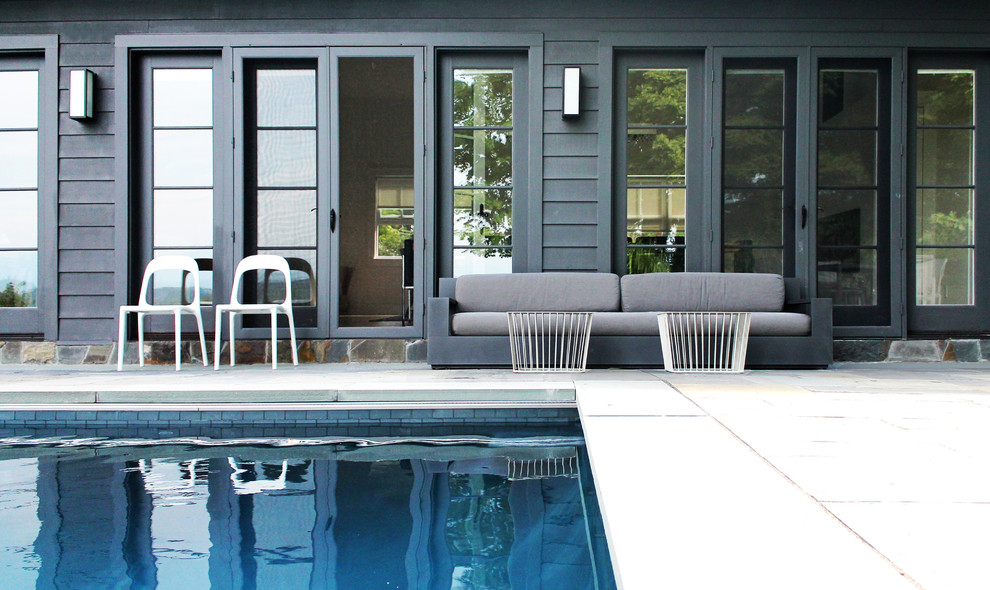 Diseño de piscina infinita moderna de tamaño medio rectangular en patio trasero con adoquines de piedra natural