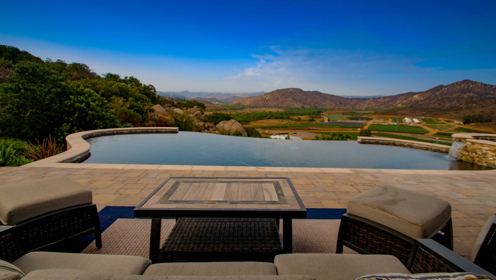 Imagen de piscina infinita mediterránea de tamaño medio a medida en patio trasero con paisajismo de piscina y adoquines de hormigón