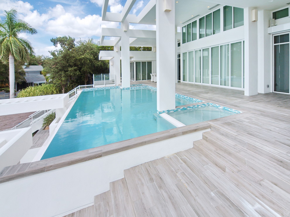Imagen de piscinas y jacuzzis infinitos minimalistas grandes rectangulares en patio trasero con suelo de baldosas