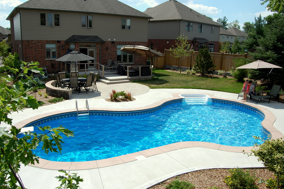 Modelo de piscina alargada tradicional de tamaño medio a medida en patio trasero con adoquines de hormigón