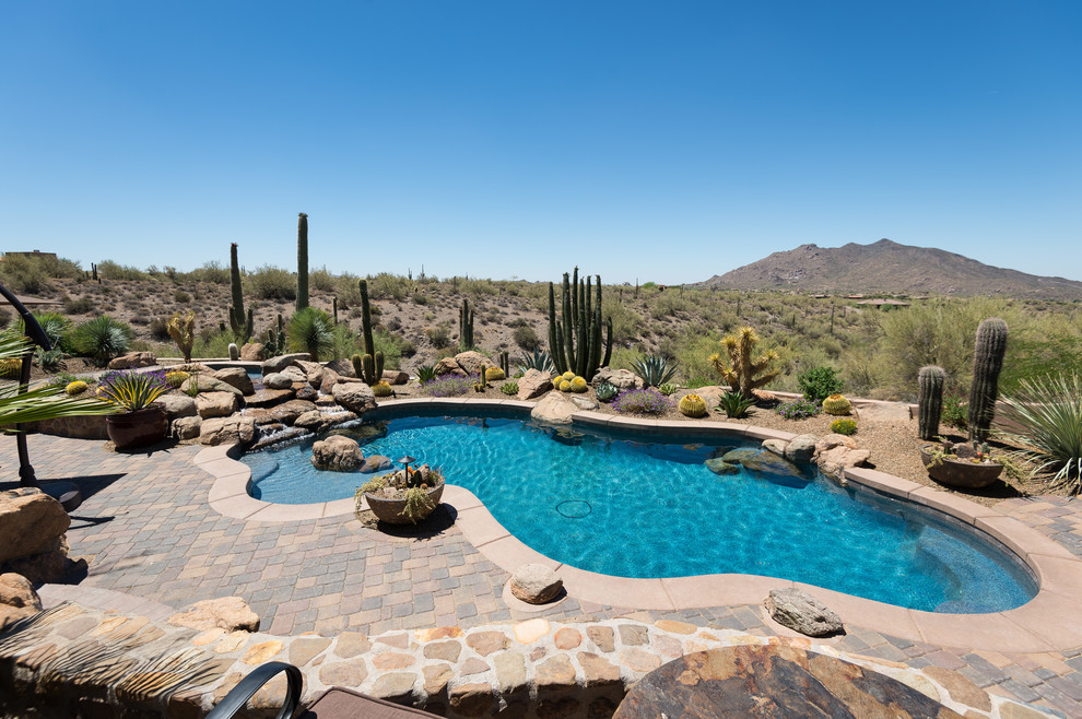 На фото: бассейн произвольной формы на заднем дворе в стиле фьюжн с фонтаном