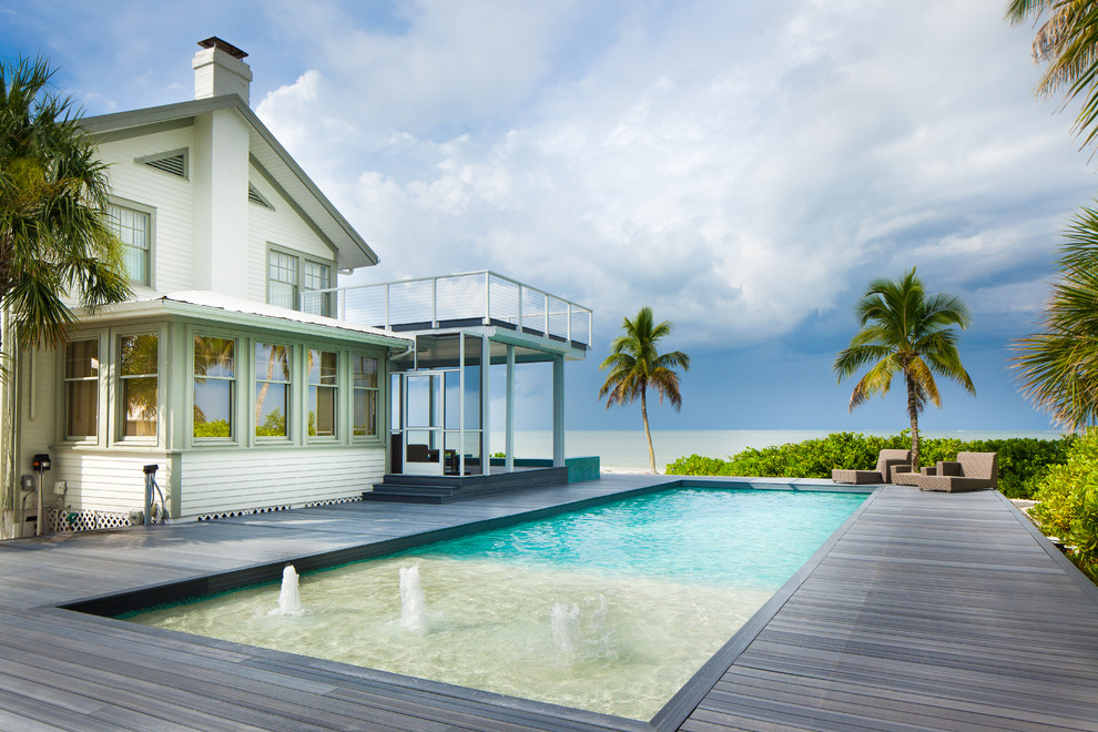 Imagen de piscina con fuente alargada costera grande rectangular en patio trasero con entablado