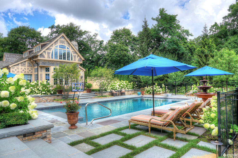 Foto de piscina con fuente tradicional de tamaño medio rectangular en patio trasero con adoquines de piedra natural