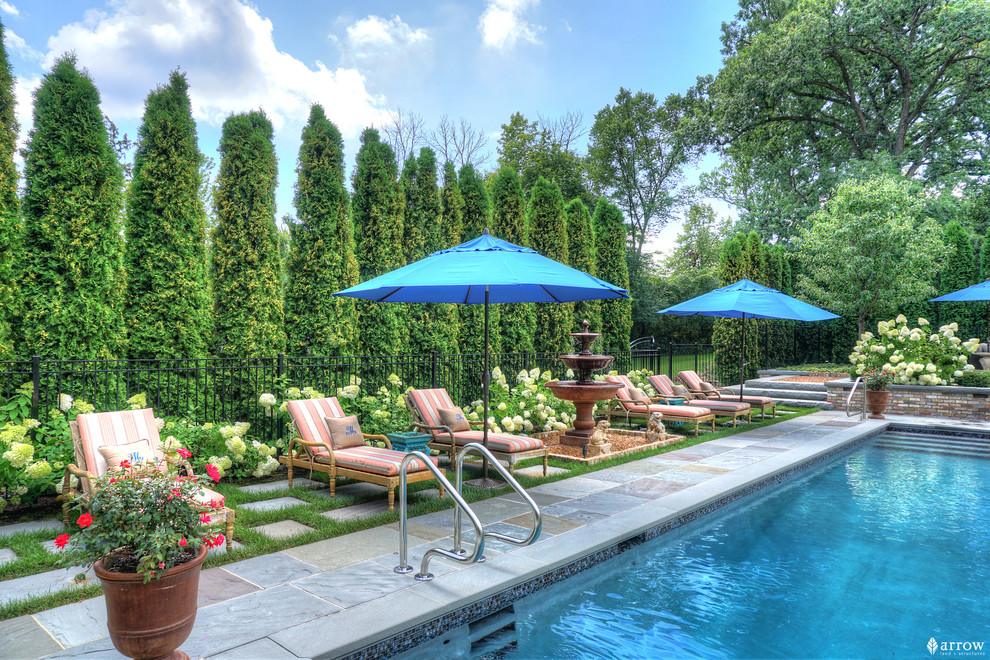 Imagen de piscina con fuente clásica de tamaño medio rectangular en patio trasero con adoquines de piedra natural