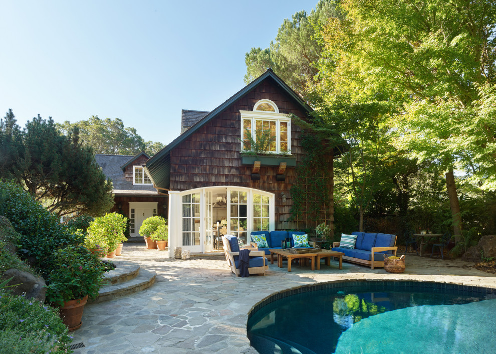 Foto di un'ampia piscina naturale chic personalizzata dietro casa con pavimentazioni in pietra naturale e paesaggistica bordo piscina