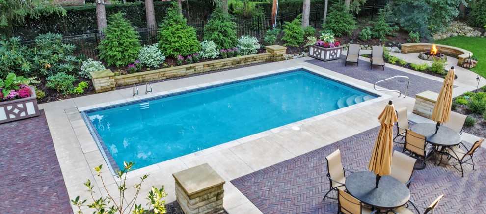 Diseño de piscina alargada tradicional de tamaño medio rectangular en patio trasero con adoquines de hormigón