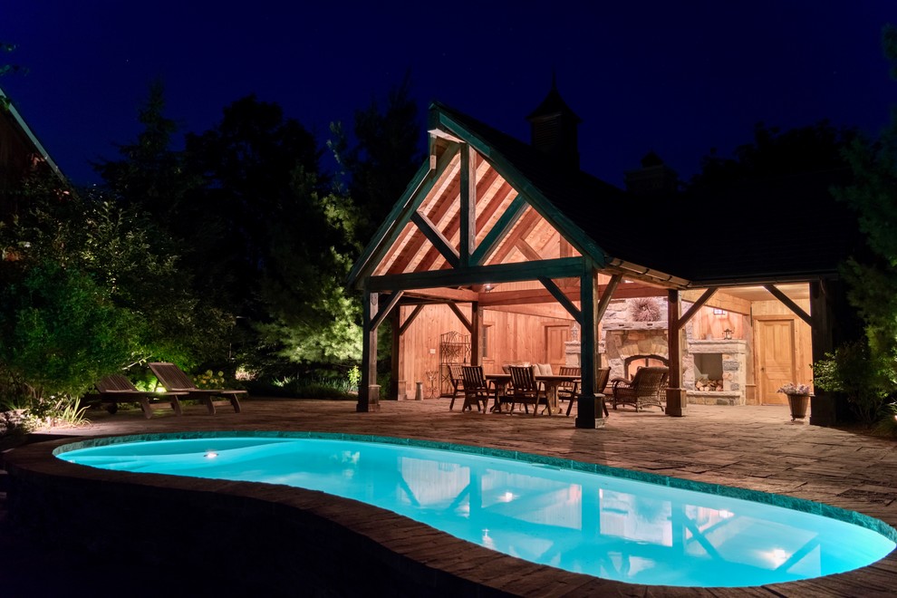 Пример оригинального дизайна: бассейн среднего размера на заднем дворе в стиле рустика с домиком у бассейна и мощением тротуарной плиткой