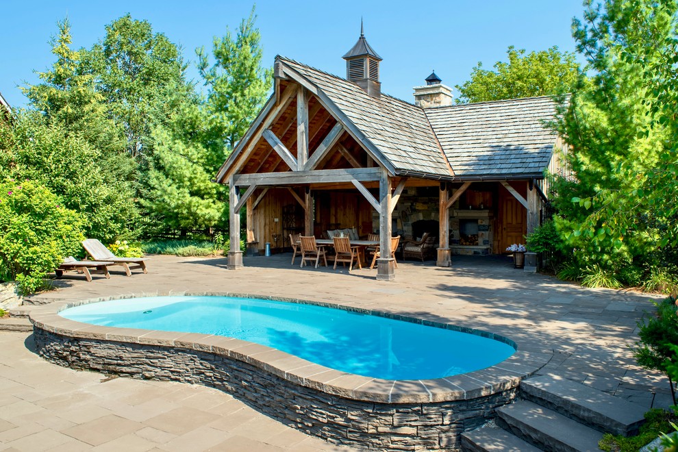 Medium sized rustic back swimming pool in Toronto with a pool house and concrete paving.