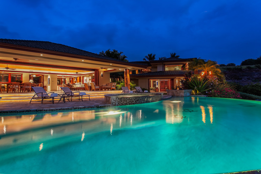 Idee per un'ampia piscina a sfioro infinito tropicale personalizzata dietro casa con fontane e pavimentazioni in pietra naturale