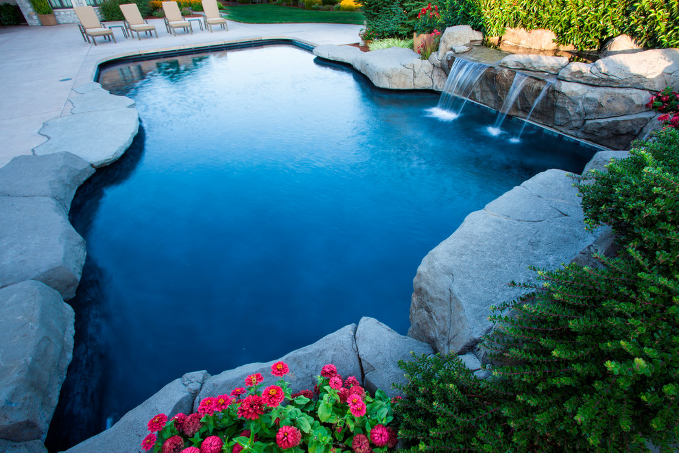 Immagine di una grande piscina country personalizzata dietro casa con fontane e cemento stampato