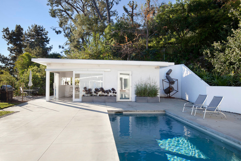 Esempio di una piscina monocorsia moderna rettangolare di medie dimensioni e dietro casa con una dépendance a bordo piscina e lastre di cemento