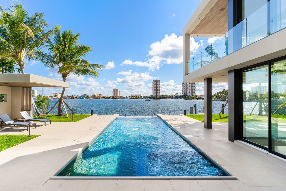 Photo of a contemporary rectangular swimming pool in Miami with tiled flooring.
