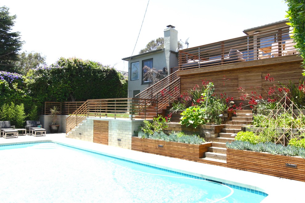 Ejemplo de piscina alargada retro grande rectangular en patio trasero con entablado