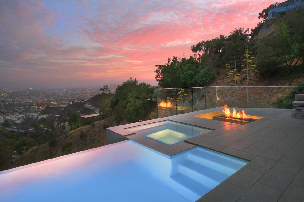 Esempio di una piccola piscina a sfioro infinito moderna personalizzata dietro casa con una vasca idromassaggio e piastrelle