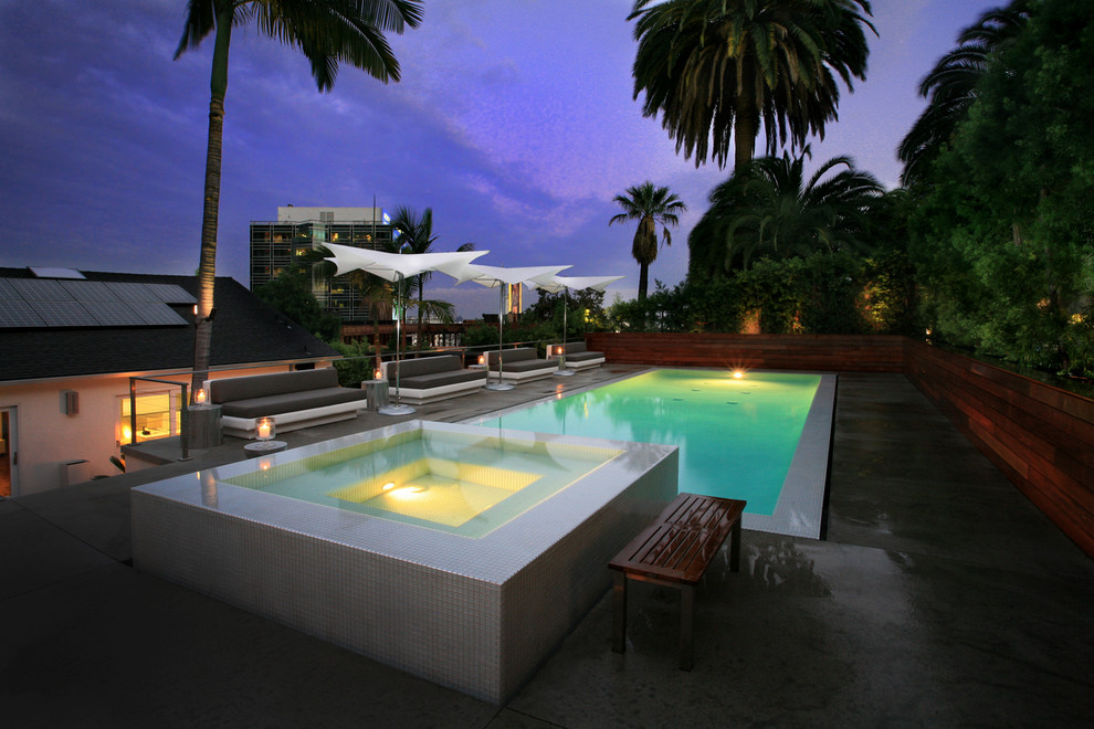 Inspiration for a large contemporary back rectangular infinity hot tub in Los Angeles with concrete slabs.