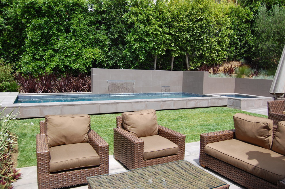 На фото: маленький прямоугольный, спортивный бассейн на заднем дворе в стиле модернизм с фонтаном и мощением тротуарной плиткой для на участке и в саду
