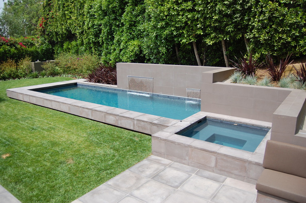 Imagen de piscina con fuente alargada moderna pequeña rectangular en patio trasero con adoquines de hormigón