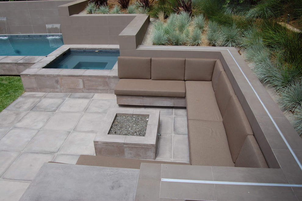 This is an example of a small modern back rectangular lengths swimming pool in Los Angeles with a water feature and concrete paving.