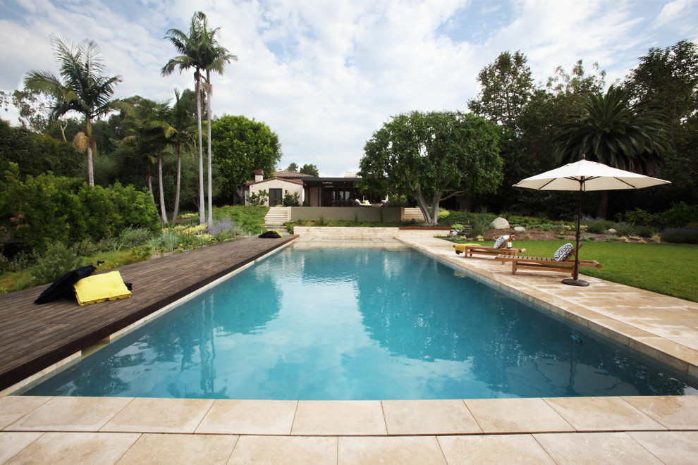 Esempio di un'ampia piscina design rettangolare dietro casa con pedane