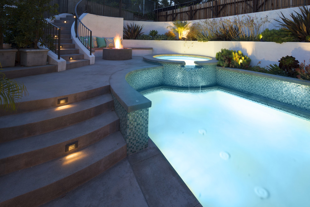 Foto di una piscina naturale chic a "C" dietro casa e di medie dimensioni con una vasca idromassaggio e lastre di cemento