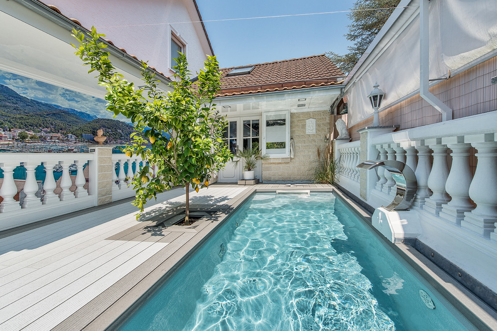 Exemple d'une piscine arrière tendance rectangle et de taille moyenne avec un point d'eau et une terrasse en bois.