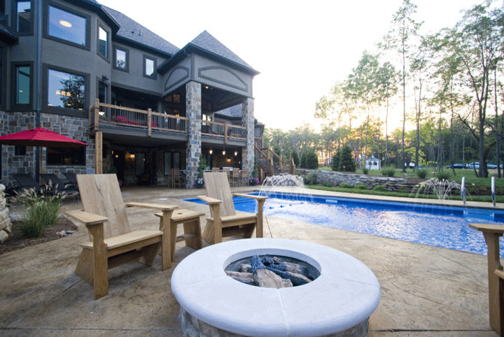 Diseño de piscina con fuente alargada de estilo americano de tamaño medio rectangular en patio trasero con suelo de hormigón estampado
