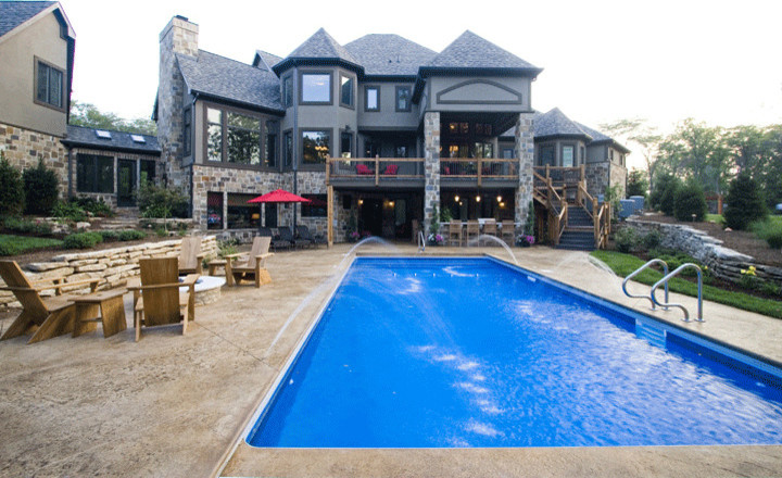 Medium sized rustic back rectangular lengths swimming pool in Indianapolis with stamped concrete and a water feature.