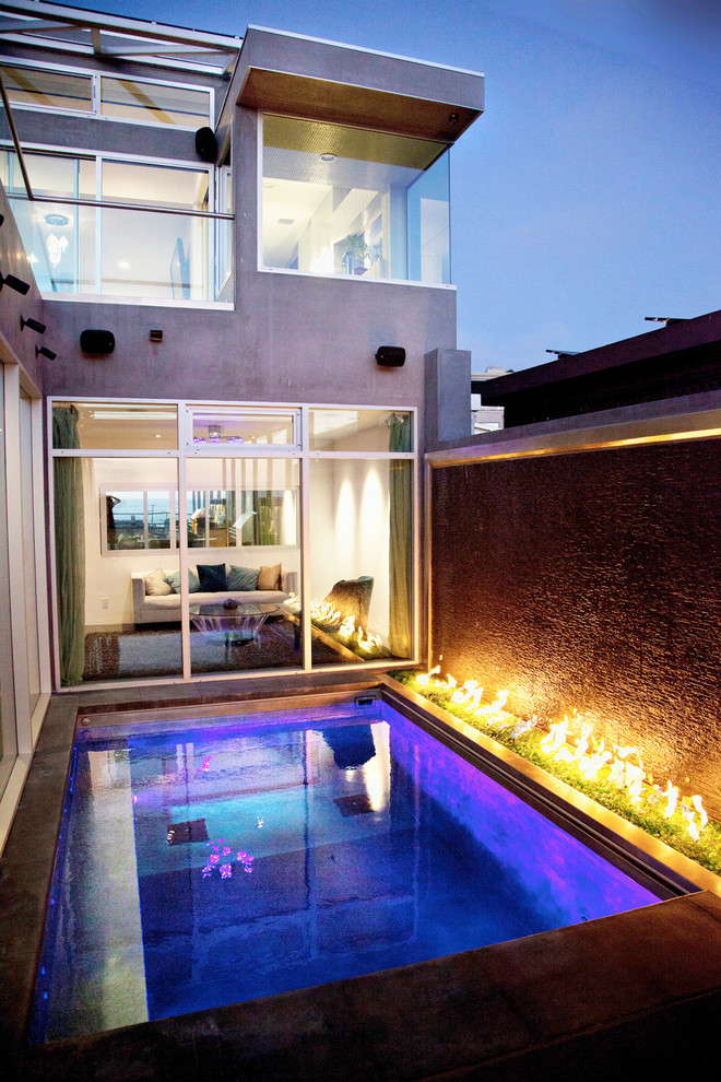 Ejemplo de piscina con fuente alargada moderna de tamaño medio a medida en patio trasero con suelo de hormigón estampado
