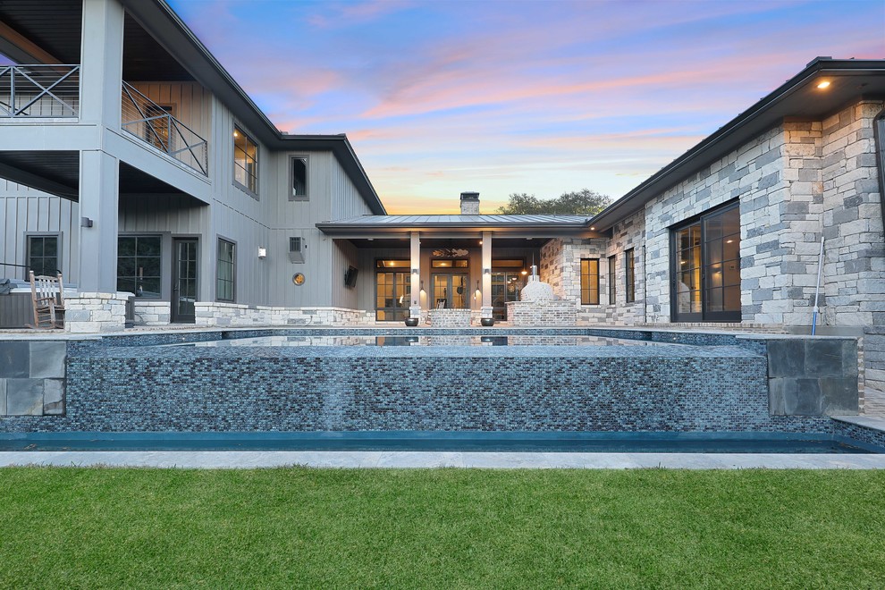 Идея дизайна: большой прямоугольный бассейн-инфинити на заднем дворе в стиле неоклассика (современная классика) с фонтаном и мощением клинкерной брусчаткой