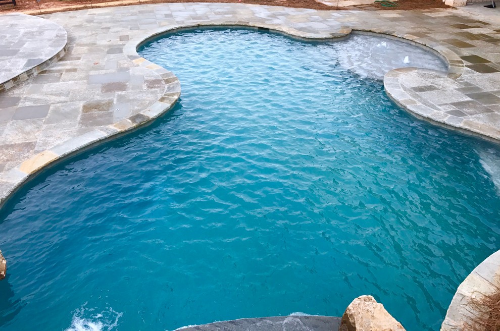 Idee per una grande piscina chic personalizzata dietro casa con un acquascivolo e pavimentazioni in cemento