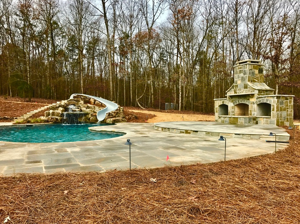 Inspiration för en stor vintage anpassad pool på baksidan av huset, med vattenrutschkana och marksten i betong