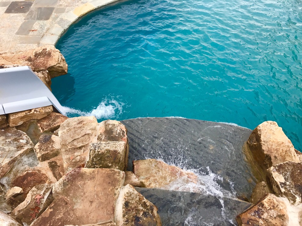 Immagine di una grande piscina classica personalizzata dietro casa con un acquascivolo e pavimentazioni in cemento